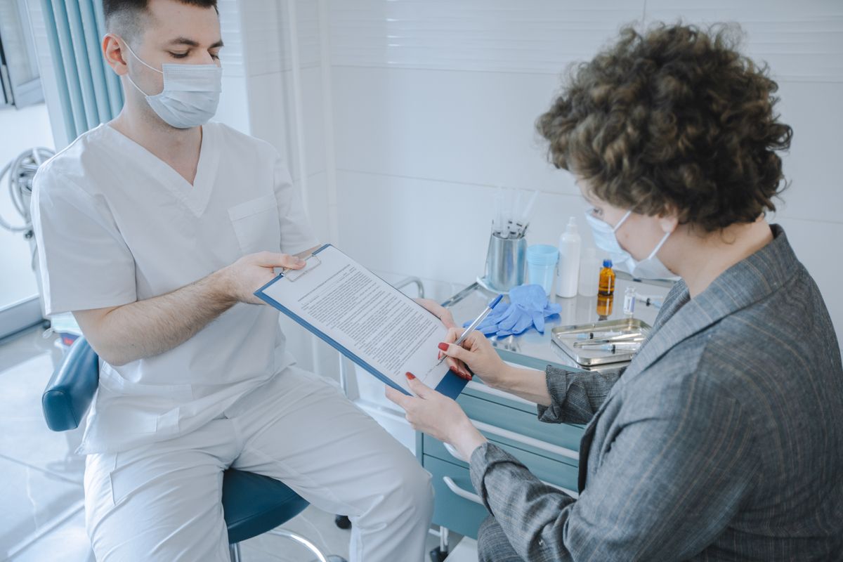 A clinician going over an intake form with a patient in an exam room, the kind of personal care a retail clinic never offered