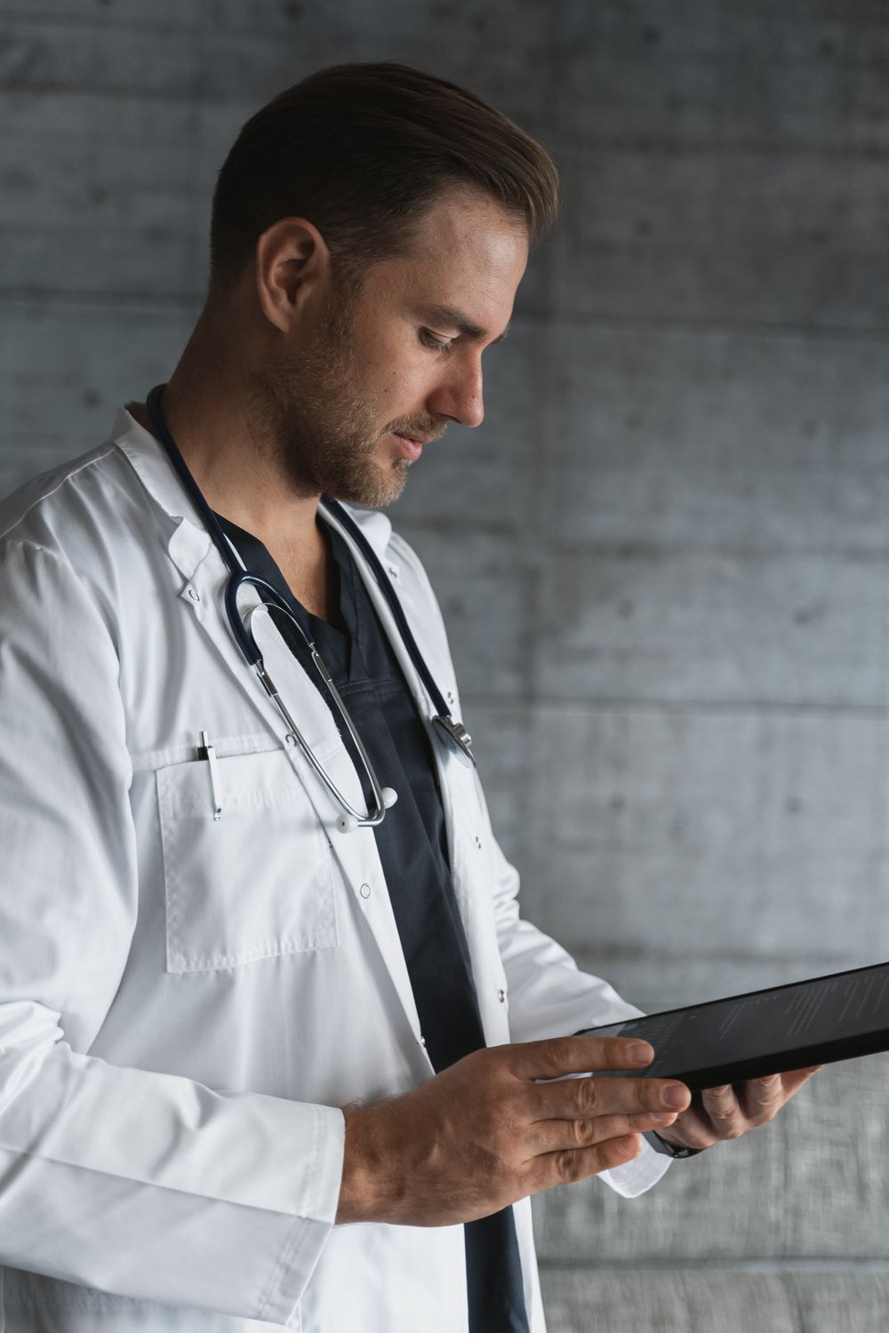 A physician in a white coat reading a tablet, weighing whether to hire a marketing agency for the practice