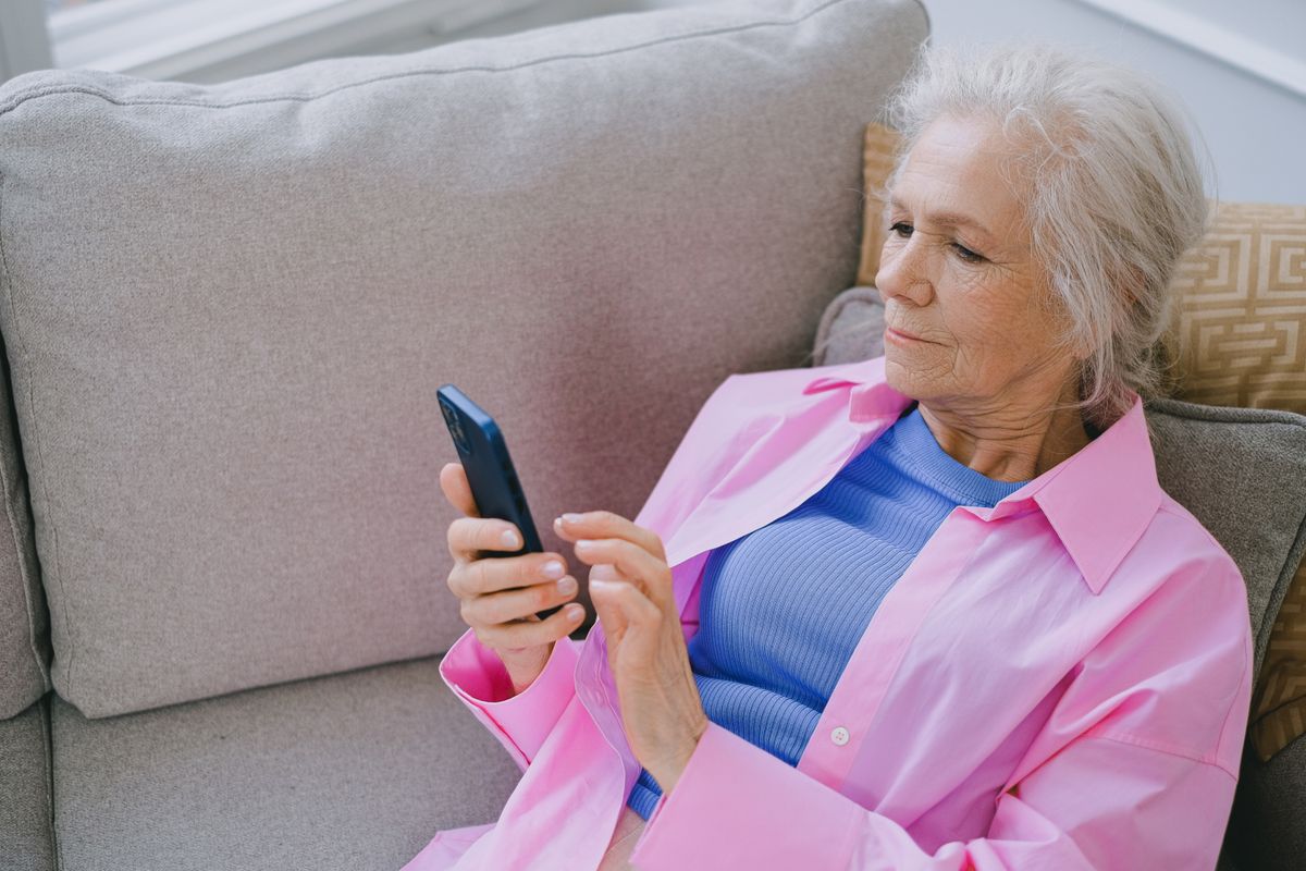 An older woman focused on her smartphone, representing a middle aged patient using AI to find a doctor