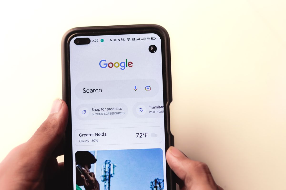 A hand holding a phone typing a search into Google, the moment a patient decides which medical practice ad to tap