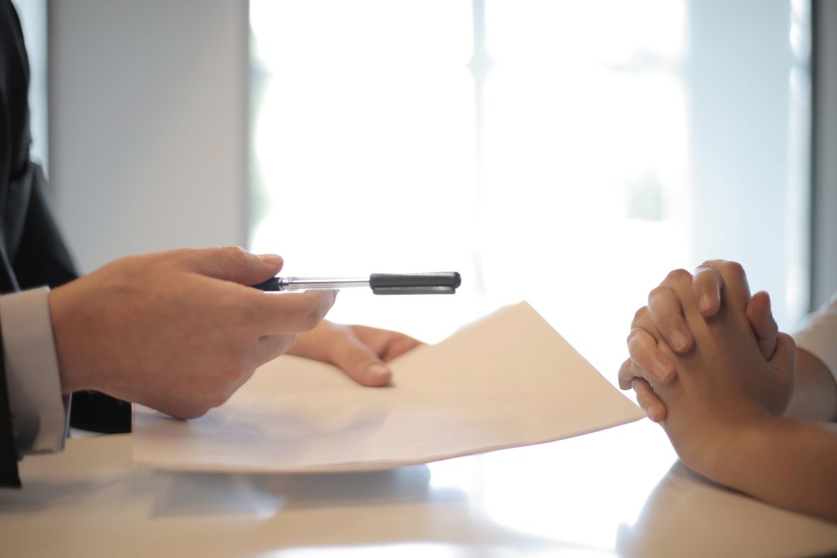 Two people reviewing and signing paperwork across a desk, like a medical practice getting its ads verified for compliance