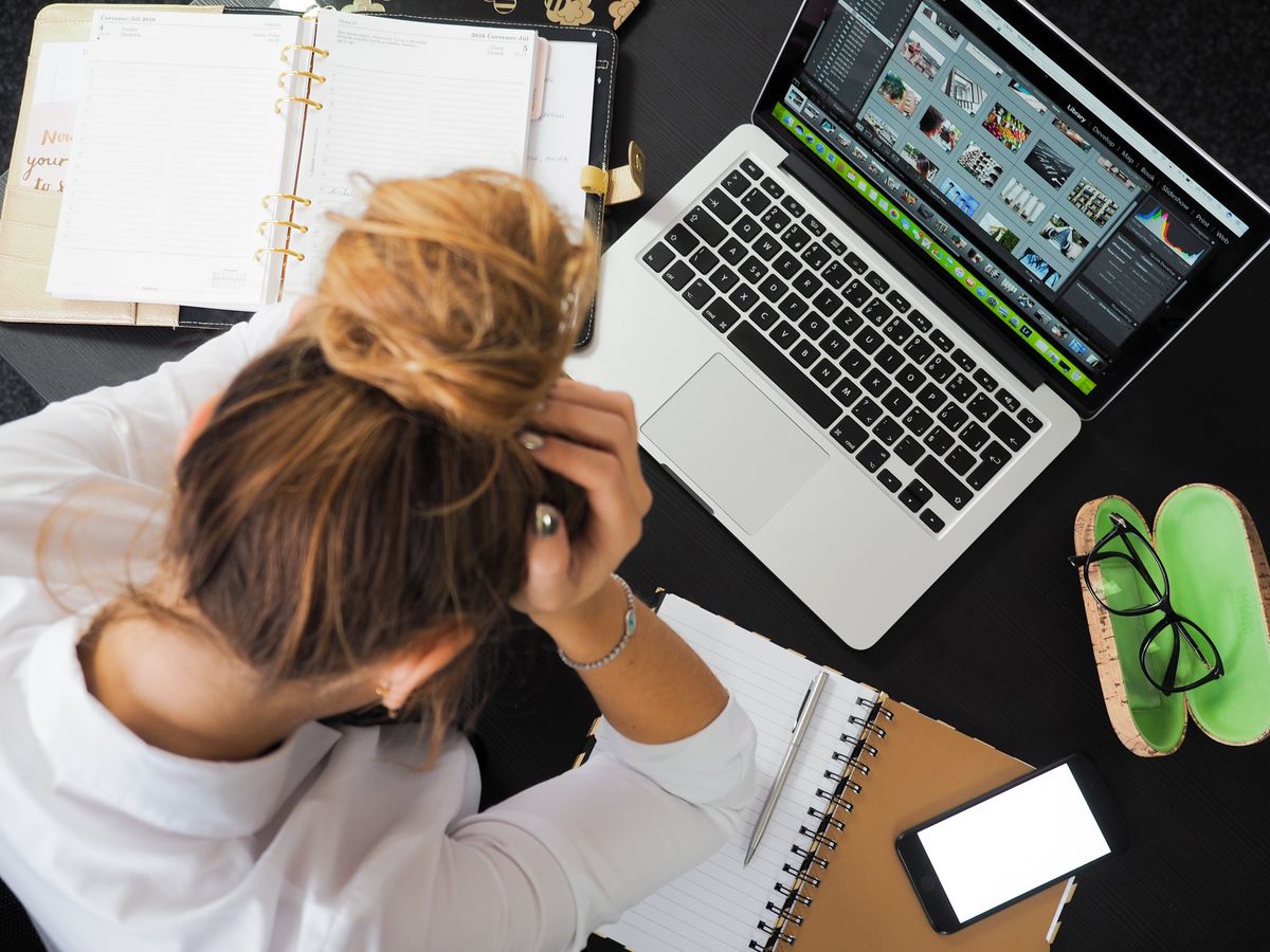 A practice owner looking frustrated at a laptop and phone, sorting through fake and junk patient leads