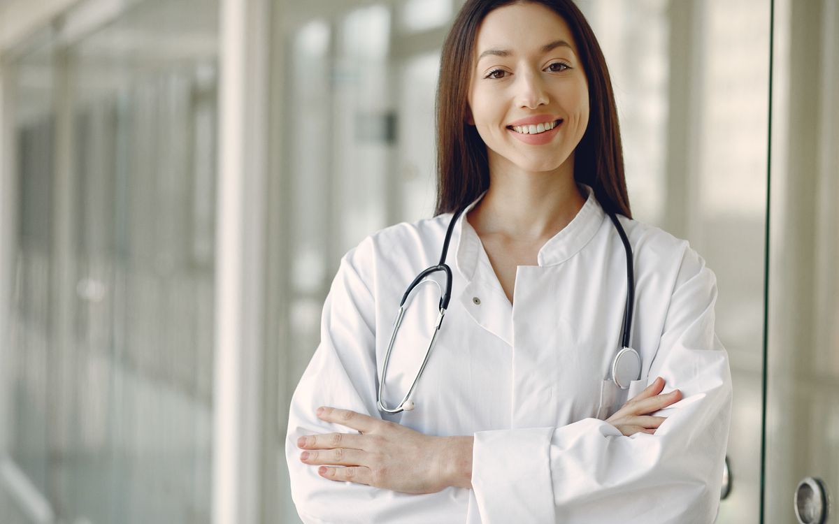 A confident doctor in a white coat standing in a clean modern clinic, the kind of trust signal that makes patients choose a more expensive practice