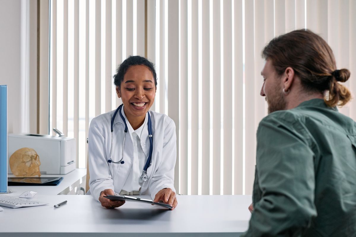 A doctor showing a tablet and explaining a treatment plan to a patient during a consultation