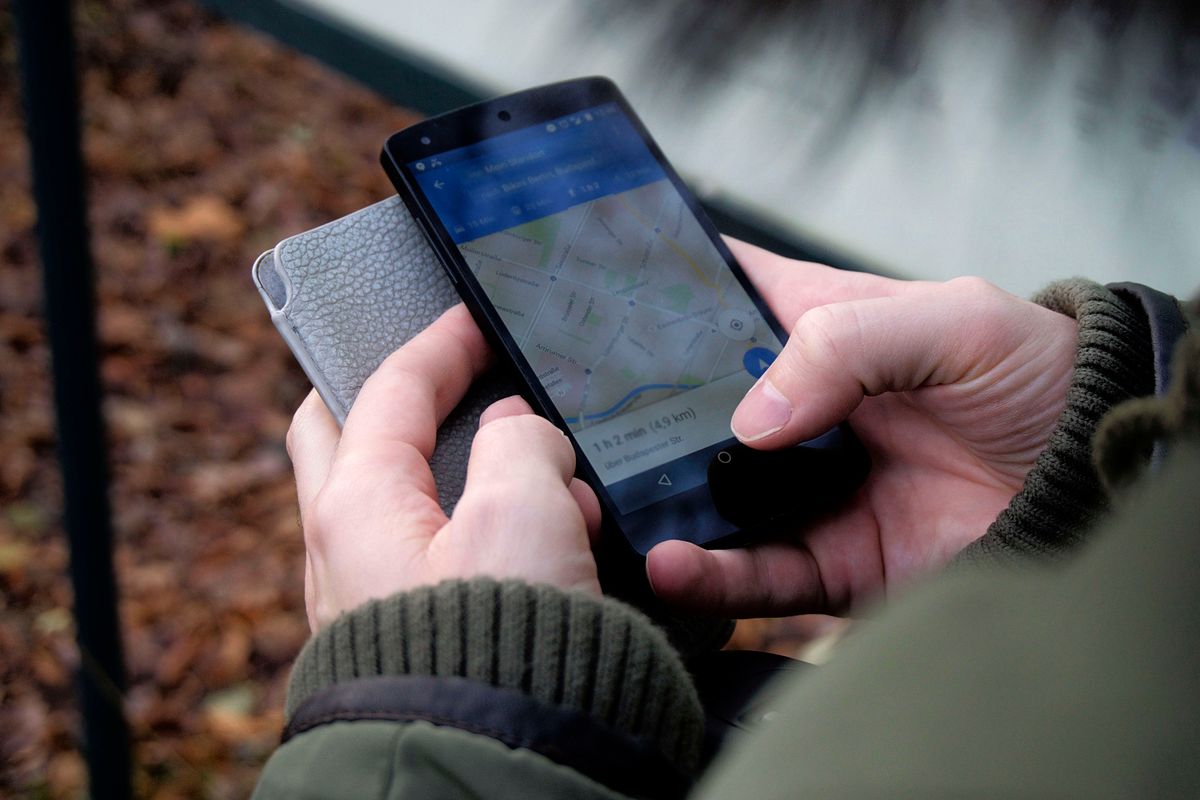 Patient holding a smartphone searching Google Maps for a doctor near me, the exact moment a practice needs to show up in local results